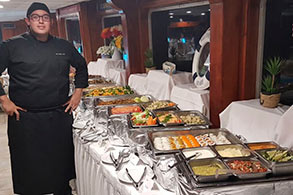 El chef posando junto a la mesa de comida buffet