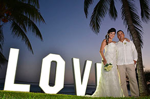 Novios posando frente a banner de LOVE en Garrafón