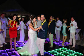 Novia e invitados bailando sobre pista de baile en la playa